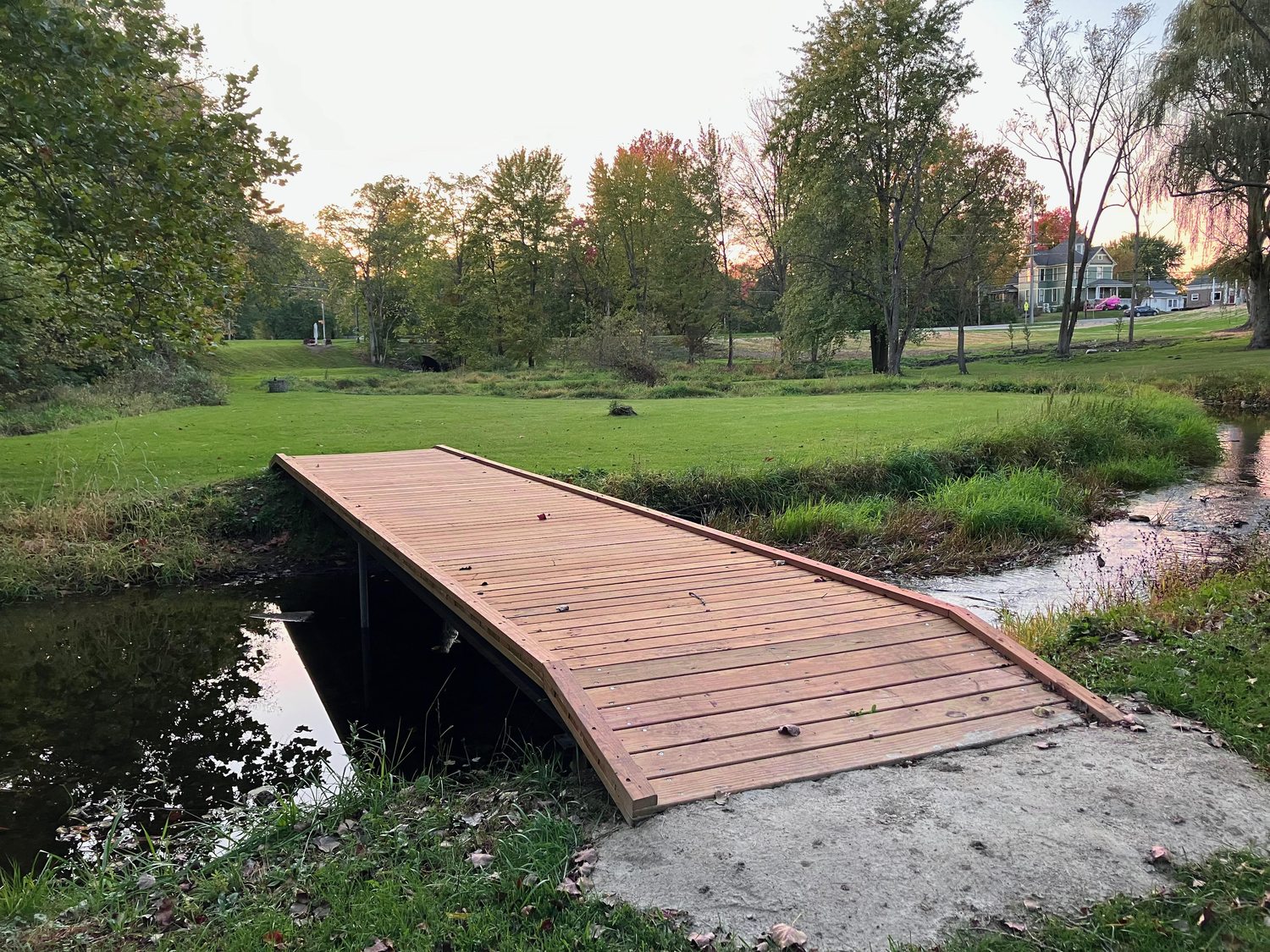 New bridge at Wolcott Park after replacement, a solid wooden walkway with a ramped deck over the creek